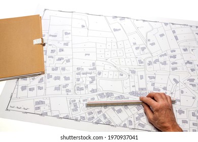 Town planning and land use planning - hand holding a measuring ruler on a cadastral map placed on a desk 