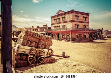 Town square as a western movie set. Spaghetti western. Cart loaded with straw bales. Travel concept - Shutterstock ID 1946491594