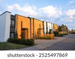 Townhouse in suburb. Modern building in green enviroment. Street with Two-story townhouses in Gated Community. Modern Townhouse along sidewalk with green lawn.Pedestrian path with flowerbed shrubs.