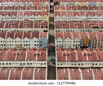 Townhouses In Melaka, Malaysia Seen From Above. Orange Roofs Made Of Clay Tile, Facades White, Some Are Another Colour. Green Car In The Middle Of The Urban Space. Compact Housing Block With Crossings