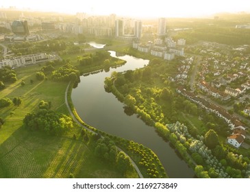 Townhouses and multi-floor home near river. River in city on sunrise, aerial view. Possible granularity, motion blur. 
