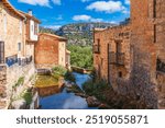 Townscape showcasing a picturesque street with a river, Orbaneja del Castillo