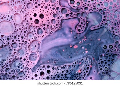 Toxic chemical acrylic oil droplets on water foam creating the idea of pollution concepts ideas and themes in bright vibrant colours, as the circle globules release on the liquid surface. 