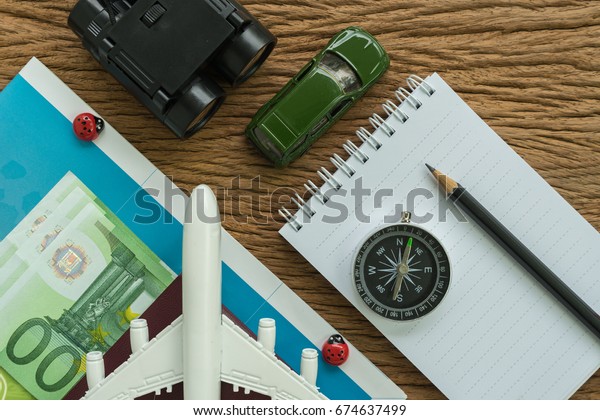 toy
airplane, compass, binoculars, pencil, paper note and miniature car
on wood table as travel planning road trip
concept.