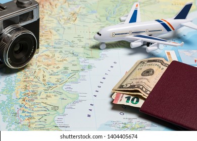 A toy airplane on a map with passport, money and a photo camera