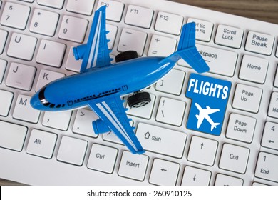 Toy airplane and plane sign on keyboard, to illustrate online booking or purchase of plane ticket or business travel concepts.