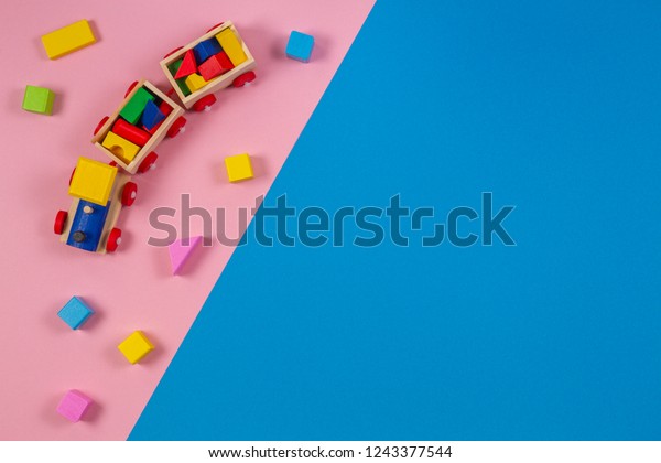 Toy background. Wooden toy train with colorful\
cubes on pink and blue\
background