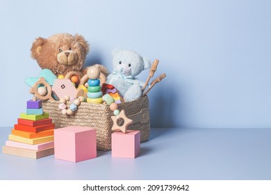 Toy box full of baby kid toys. Container with teddy bear, wooden rattles, stacking pyramid and wood blocks on light blue background. Cute toys collection for small children. Donation. Front view - Shutterstock ID 2091739642