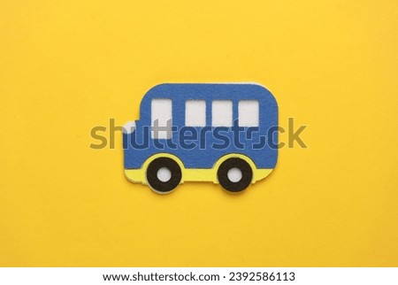 Toy bus made of felt on yellow background.