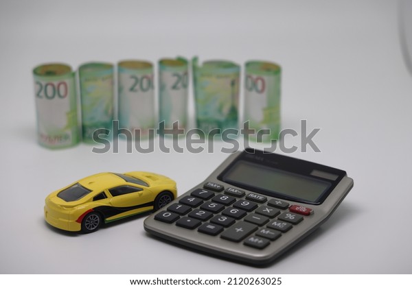 A toy car and\
banknotes lie on a kitchen electronic scale next to a calculator,\
the cost of operating a car.
