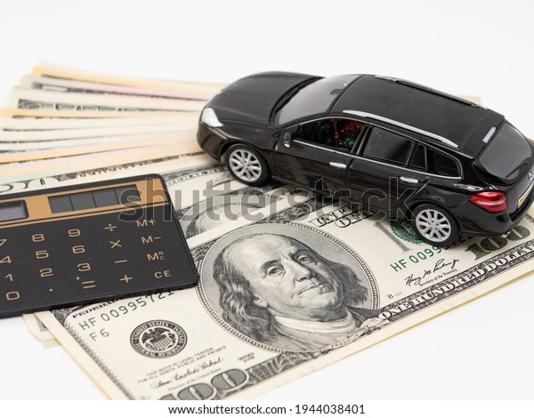 Toy car and calculator lie on american\
banknotes, mortgage and car\
insurance