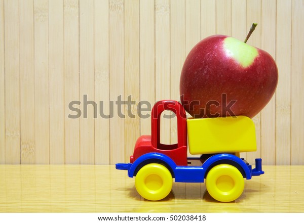 Toy car carrying a\
apple on the table