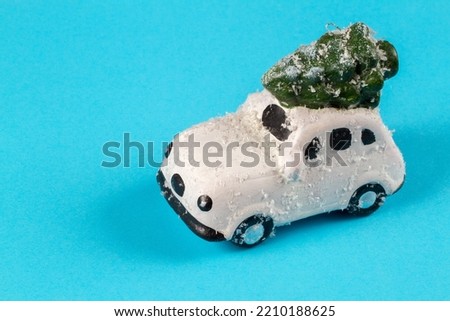 Toy car with Christmas tree on a blue background. Toy transportation of a Christmas tree.