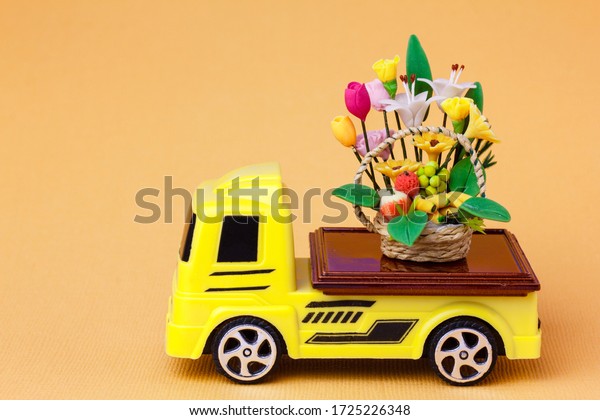 toy  car delivering a basket of flowers\
and fruits. Gifts with home delivery\
concept.