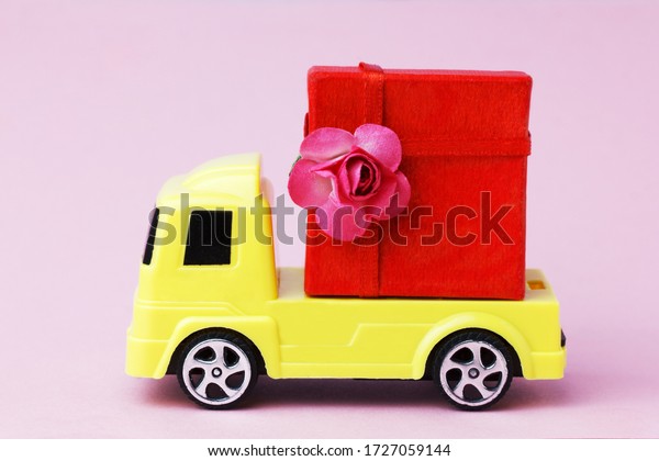 toy car delivering a large present red box. \
Sending gifts with home\
delivery.