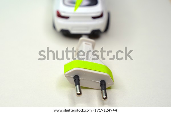 Toy car and electrical plug. Electric car and green\
car concep. The European Union wants to reach zero-emission road\
mobility by 2035.