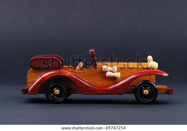 A toy car made of wood on\
black