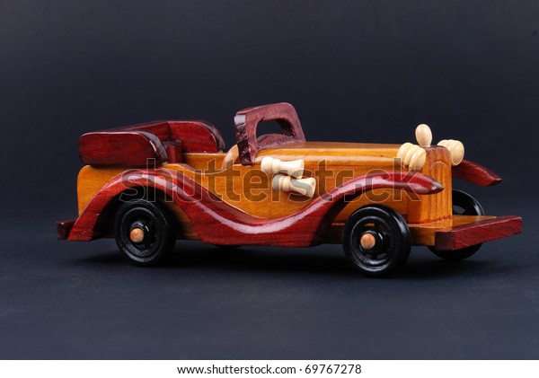 A toy car made of wood on\
black