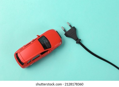 Toy car model with an electric plug on blue background. Electric car