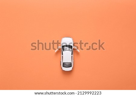 Toy car model with open doors on pink background. Top view