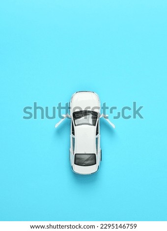 Toy car model with open doors on blue background. Top view