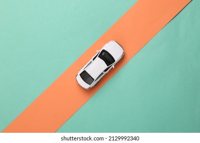 Toy car model rides on a pink stripe on a blue background. Top view