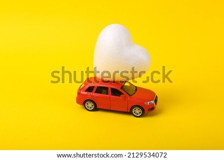 Toy car model with a saddle on a yellow background. Love romantic concept