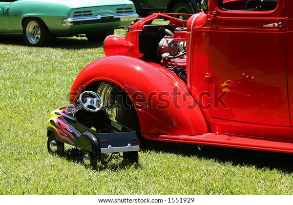 Toy car next to a\
classic car at a car show