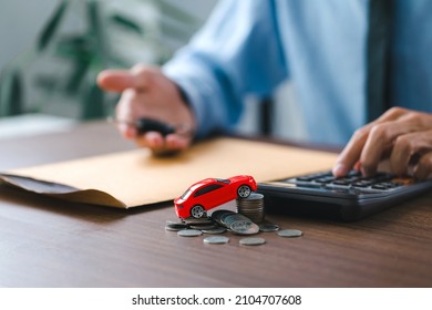  Toy car on stack coins and man holding the key car in hand. after completes the insurance policy or rental documents. Car insurance concept