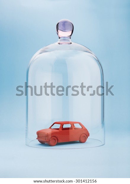 Toy\
car protected under a glass dome on blue\
background