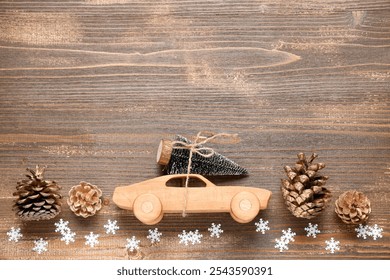 Toy car with small Christmas tree and pine cones on wooden background - Powered by Shutterstock