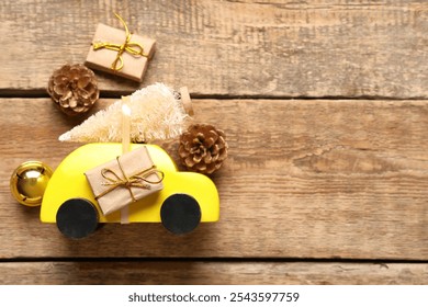 Toy car with small Christmas tree, pine cones and gift boxes on wooden background - Powered by Shutterstock