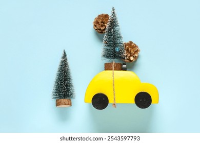 Toy car with small Christmas trees and pine cones on blue background - Powered by Shutterstock