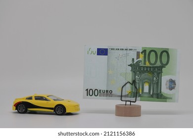 A Toy Car Stands Next To A Banknote On A Stand. Accurate Financial Calculation When Buying A Car