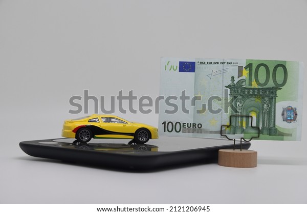 A toy car stands on\
an electronic scale next to a stand with a banknote, the concept of\
determining the cost of a car when selling, car insurance and car\
loans