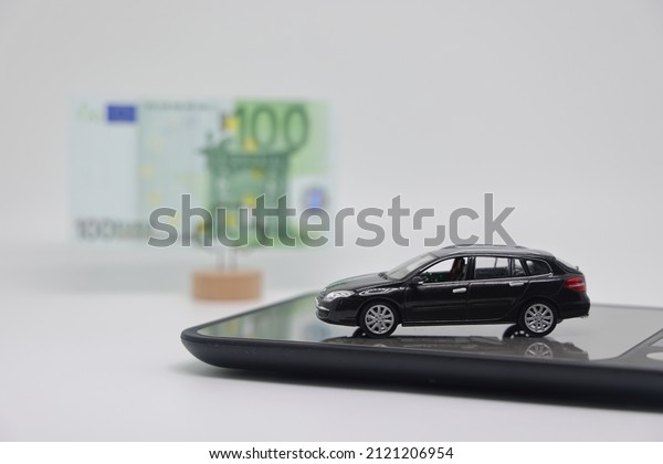 A toy car stands on\
an electronic scale next to a stand with a banknote, the concept of\
determining the cost of a car when selling, car insurance and car\
loans