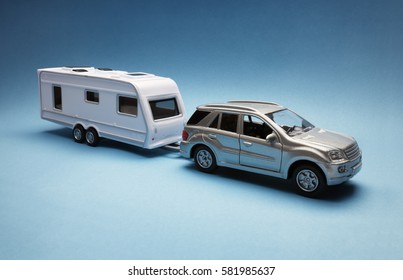 Toy Car Towing A Caravan Of Generic Design On Blue Background