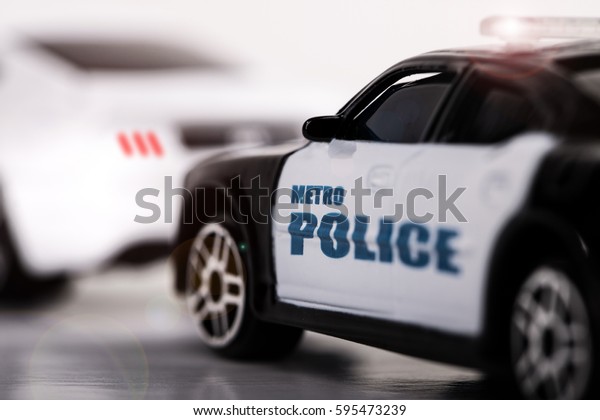 Toy Car\
Traffic Stop\
Close view of a toy police car behind another plain\
white toy car as if it was a traffic\
stop.