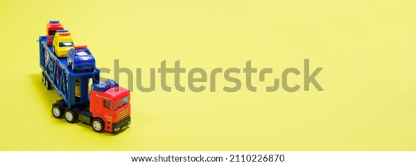 Toy car transporter\
with cars on a yellow background with place for text, copy space,\
for a toy store.