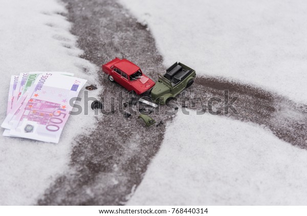 Toy cars and Euro crash on\
a slippery snowy road, the concept of spending money on auto\
repair.