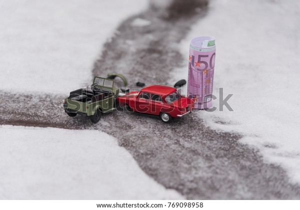 : Toy cars and Euro crash\
on a slippery snowy road, the concept of spending money on auto\
repair.