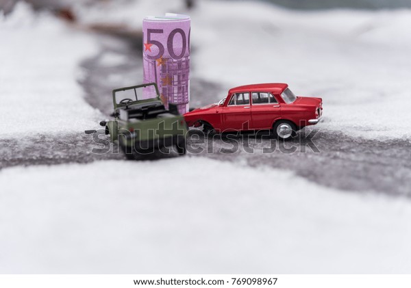 : Toy cars and Euro crash\
on a slippery snowy road, the concept of spending money on auto\
repair.
