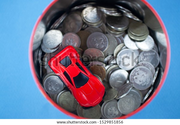 toy cars in a piggy Bank with coins, the concept of\
earning on cars