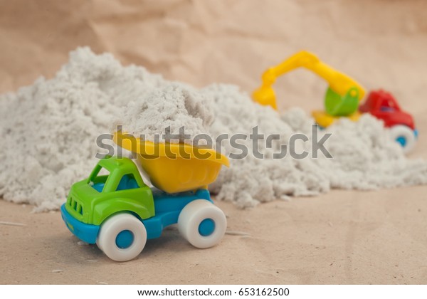toy\
cars in sand quarry. Colorful toy cars on construction site.\
Construction, mining, construction equipment at\
work