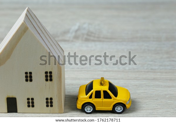 Toy cars and wooden houses in concept\
of buying housing and insurance or Travel\
concept.