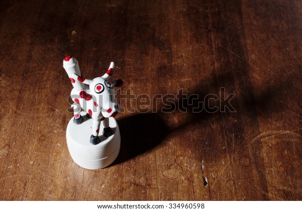 Toy cow\
with articulated parts on wooden\
background.