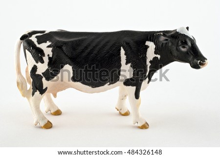 Toy cow isolated on a white background. Black and white spotted rubber or plastic cow. Farm animals. 