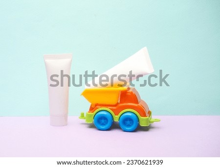 Toy dump truck with cream tubes on a pastel background