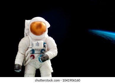 Toy Figure Of An Astronaut On The Background Of The Earth