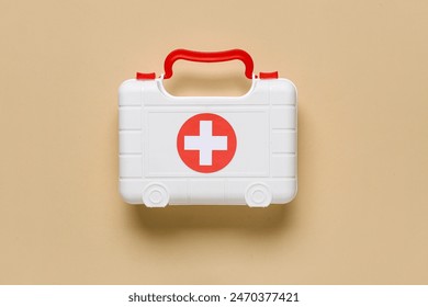 Toy first aid kit on beige background. Top view